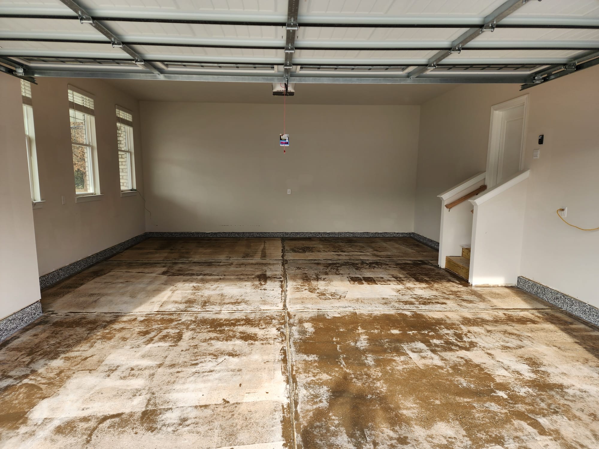 Garage floor before epoxy coating with stained and uneven concrete surface